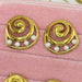 Set of gold earrings with pearls and gemstones on a pink velvet surface