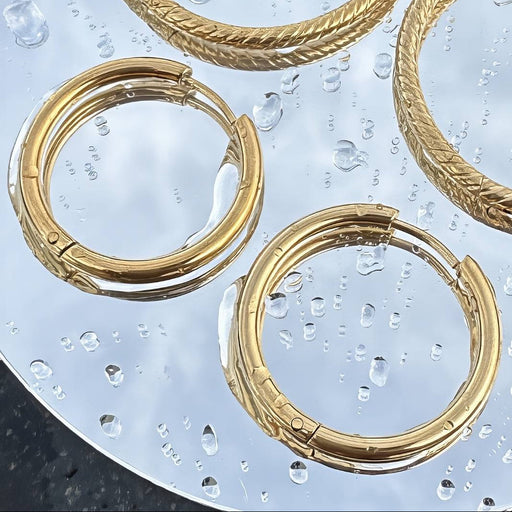 Gold earring hoops with mirror background and water droplets