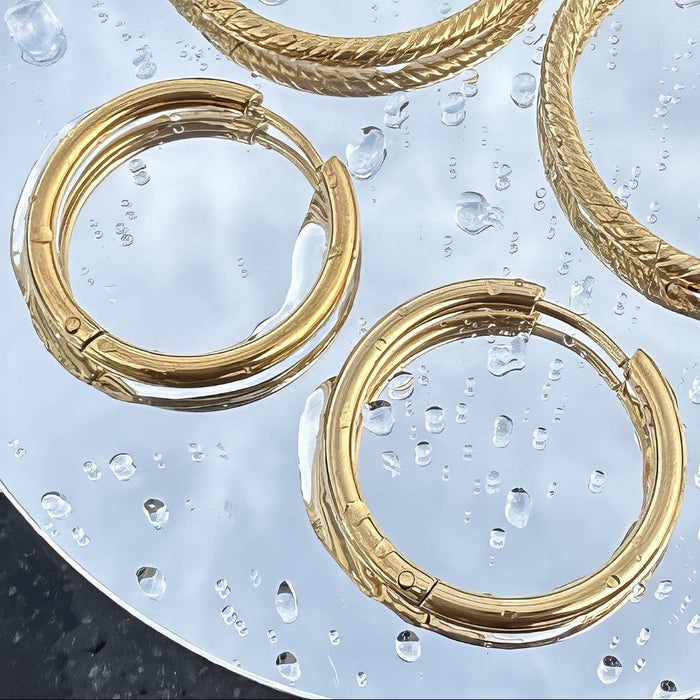 Gold earring hoops with mirror background and water droplets