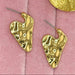 Gold earrings on a pink textured surface