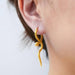 Gold snake shaped earring worn by a person on a light background
