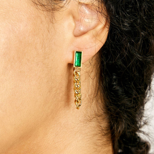 Gold earring with green gemstone worn by a person