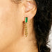 Gold earring with green gemstone worn by a person
