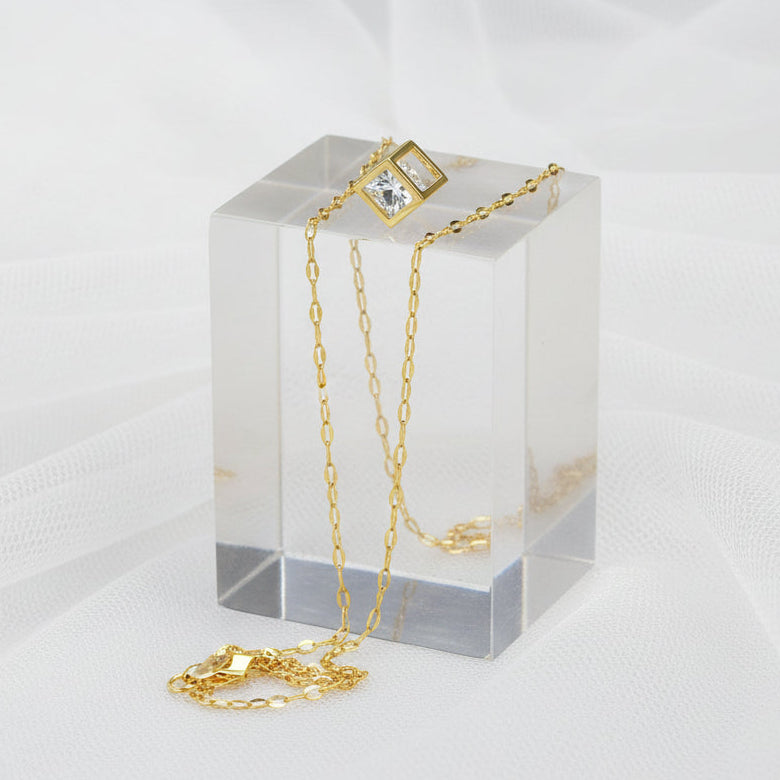 Gold necklace with a clear pendant on a white background