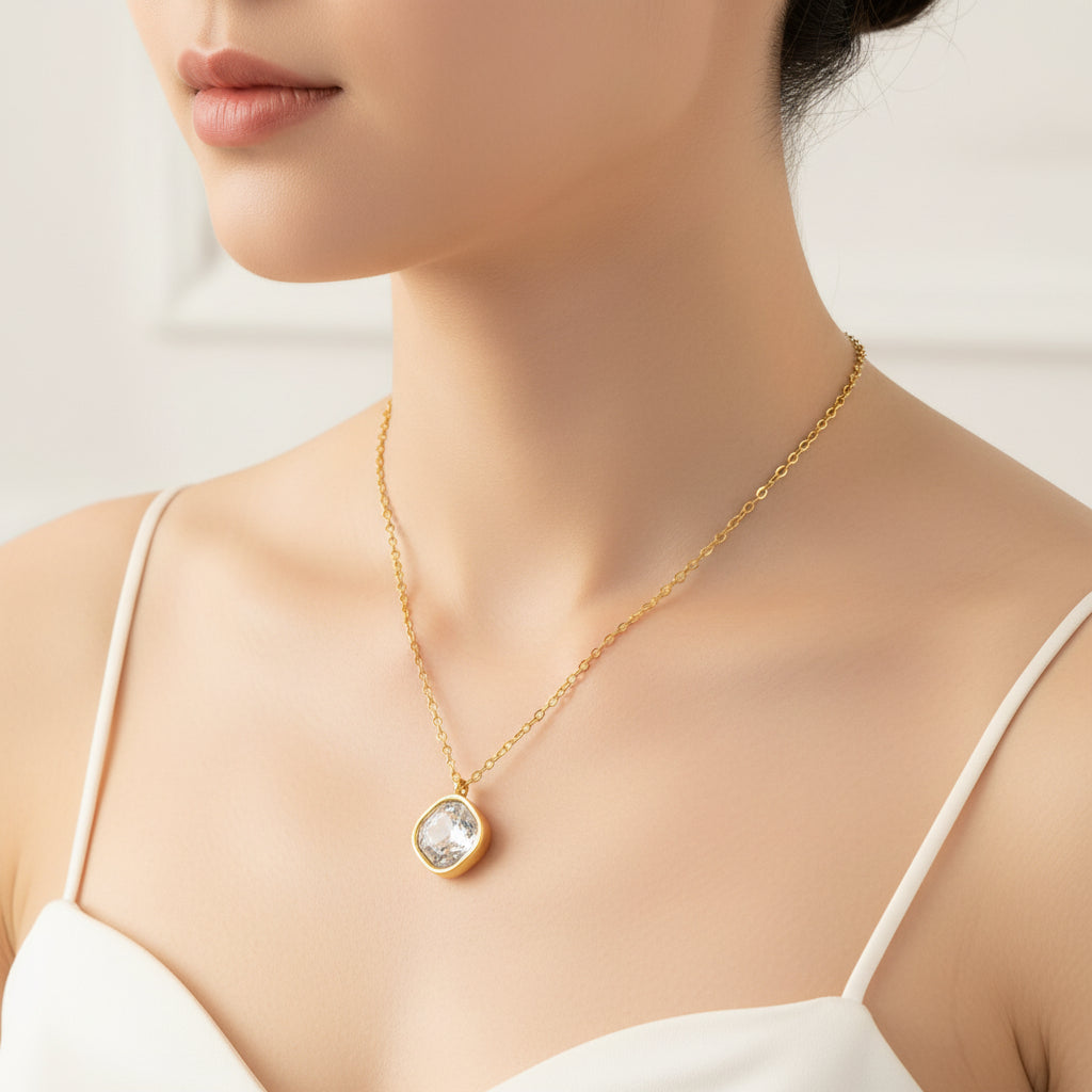 Gold necklace with a pendant on a model wearing a white top against a neutral background