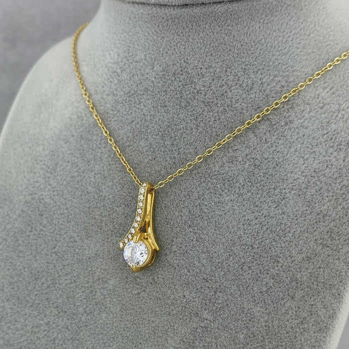Gold necklace with a diamond pendant on a gray mannequin bust.