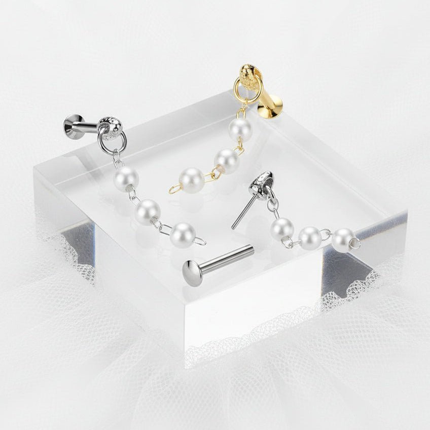 Set of pearl earrings and a gold earring on a clear stand against a white background