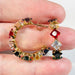 Colorful gemstone hoop earrings held between fingers against a neutral background
